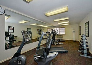 A gym with treadmills, elliptical machines, and a weight rack.