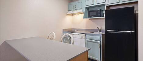 A compact kitchen with a grey countertop, a black refrigerator, and light blue cabinets.