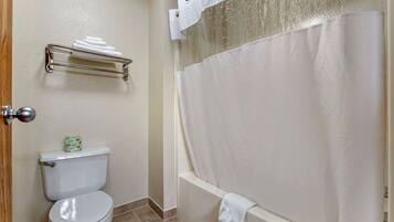 A bathroom with a toilet, a towel rack, and a bathtub with a shower curtain.