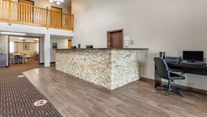 A hotel lobby with a reception desk, a computer station, a dining area, and a staircase to an upper level. - Quality Inn Creston (Creston)