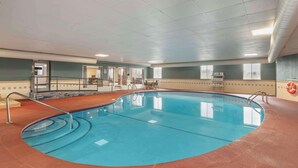 Een binnenzwembad met helder water, omringd door een rode vloer en muren, met een plafond met inbouwverlichting en een zichtbare luchtuitlaat.'