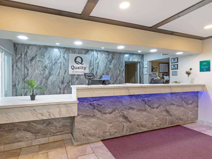 En hotellreception med en marmorliknande design, en klocka och en skylt med texten ”Kvalitet – Choice Hotels”.
