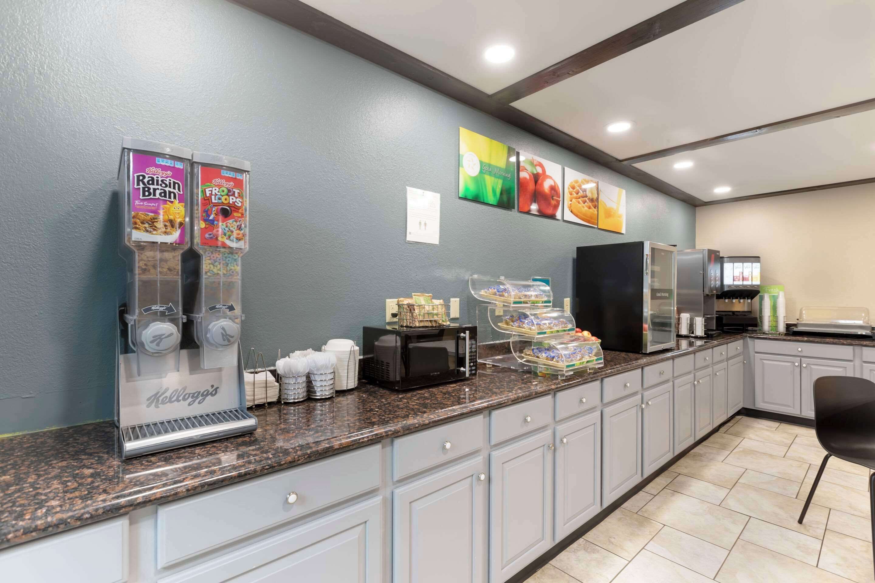 Una barra de desayuno con dispensadores de cereales Kellogg's, microondas y cafetera.