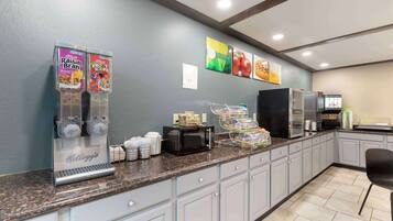 Una barra de desayuno con dispensadores de cereales Kellogg's, microondas y cafetera.