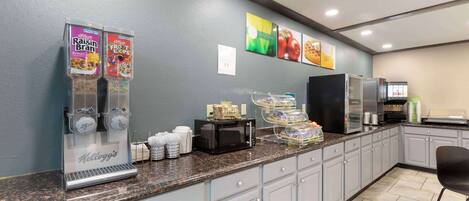 Una barra de desayuno con dispensadores de cereales Kellogg's, microondas y cafetera.