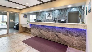 Een hotel receptie met een marmeren balie, een klok en een receptie bureau.
