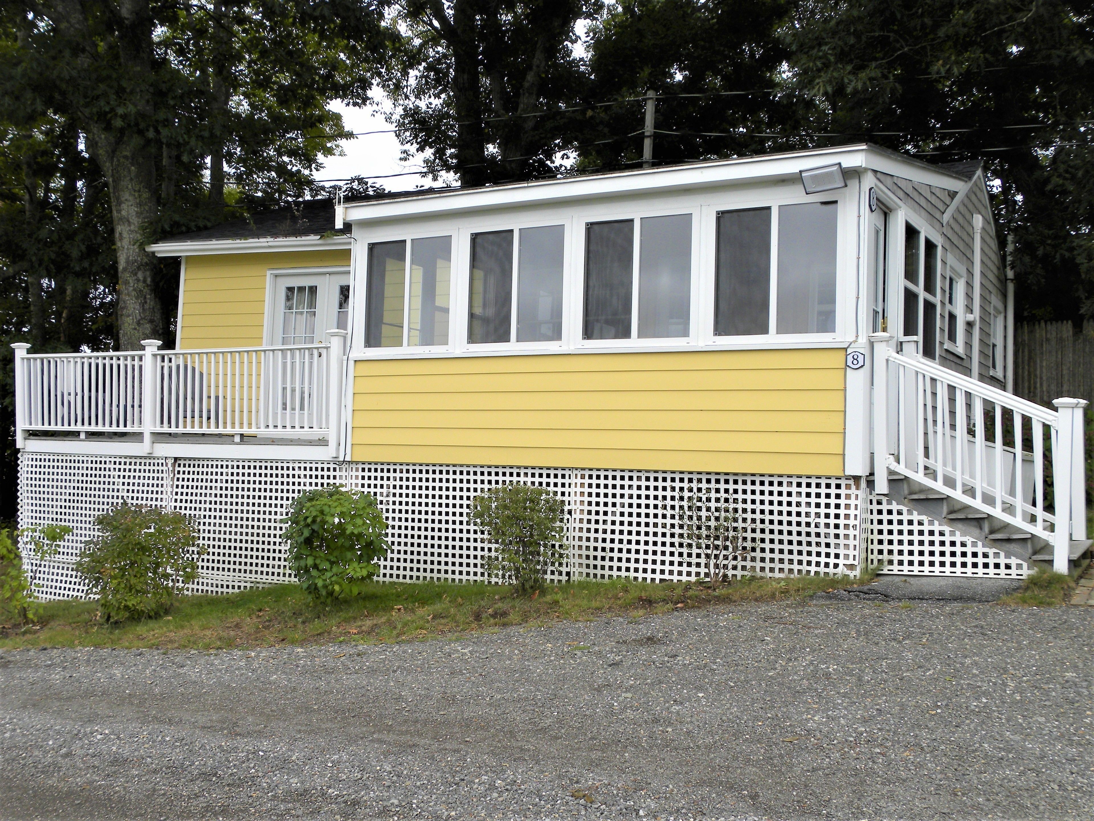 A two-story building with a yellow and white exterior, a white balcony, and a white fence.