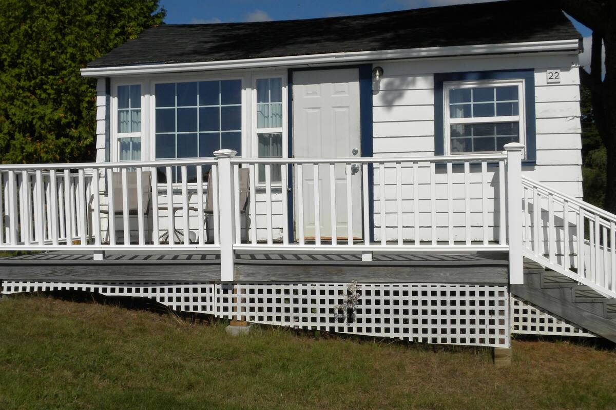 A two-story house with a white exterior, a front porch with a railing, and a garage door.