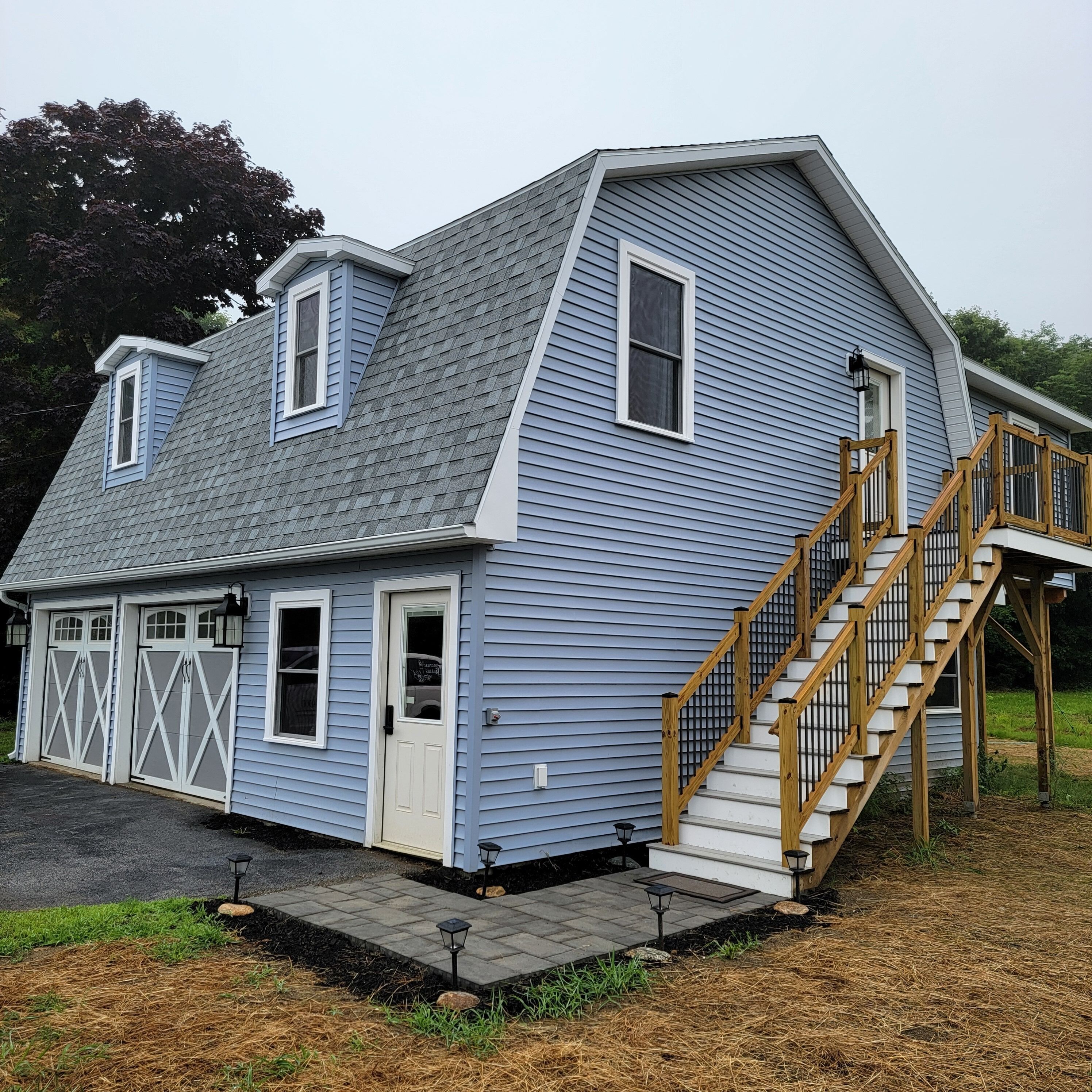 A two-story house with a garage, a front door, and a wooden staircase leading to the second floor.