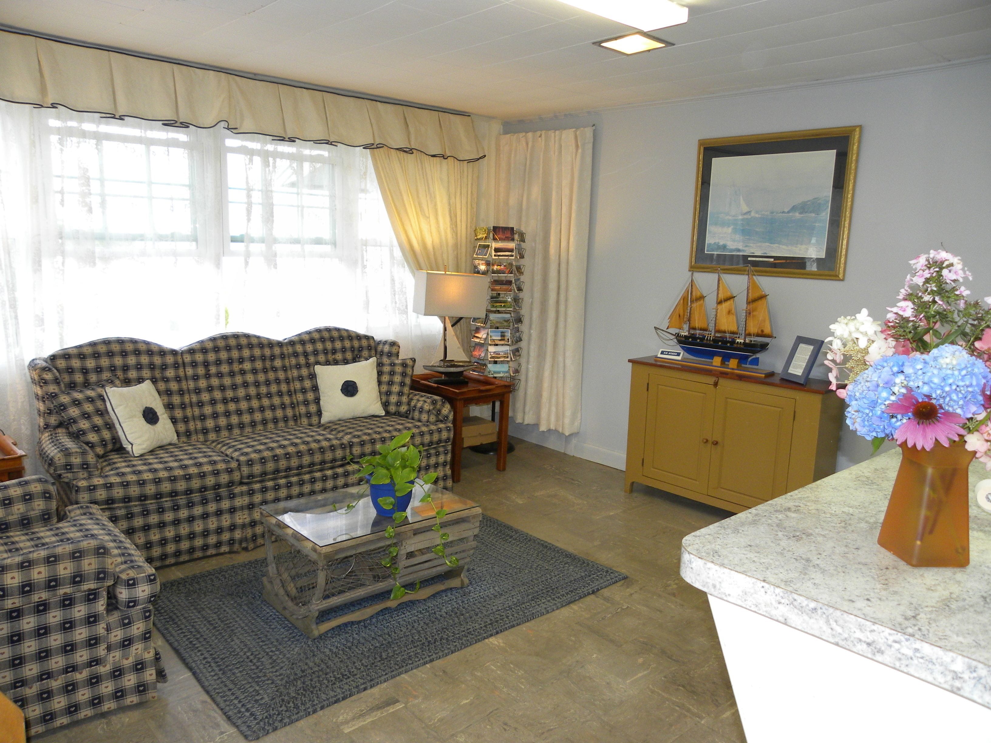 Ein Wohnzimmer mit einem karierten Sofa, einem Couchtisch mit einer Pflanze, einem Holzkabinett und einem gerahmten Bild an der Wand.
