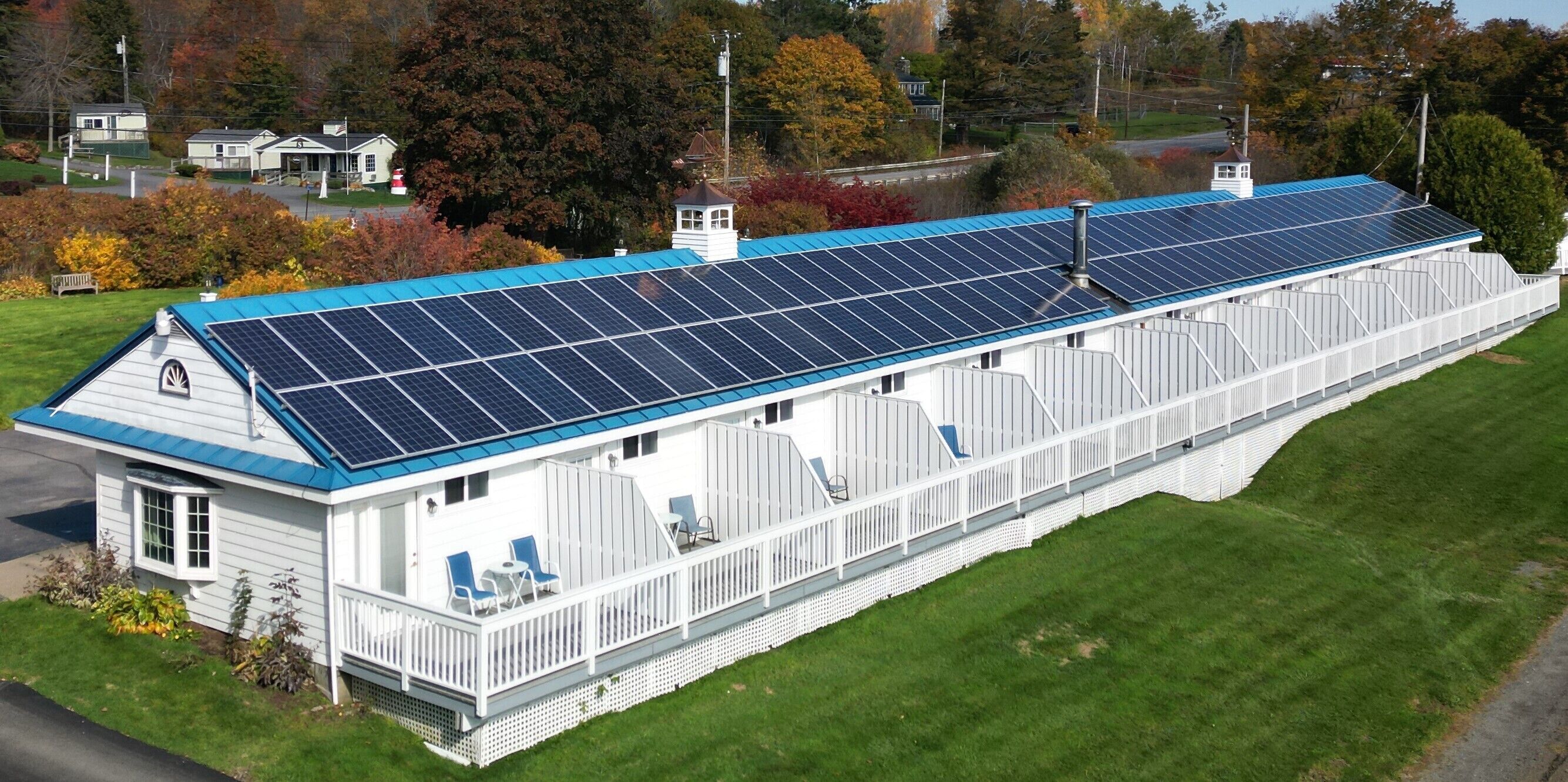 Un long bâtiment blanc, doté d’un toit bleu et de panneaux solaires.