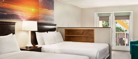 A hotel room with two beds, a nightstand with a lamp, a large painting of a sunset, a wooden headboard, and a balcony with a view.