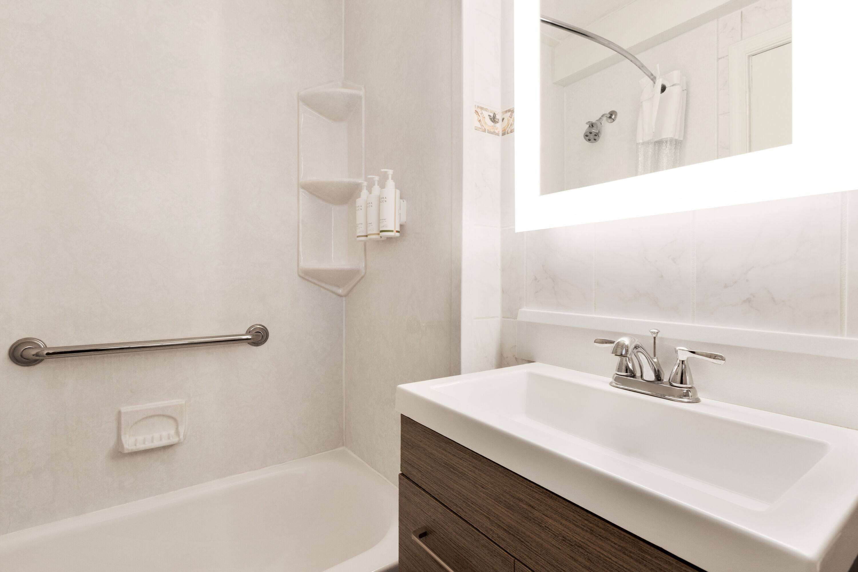 A bathroom with a white sink, a mirror, and a shower area.