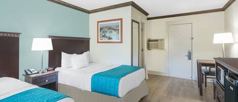 Habitación de hotel con dos camas, un escritorio, una silla, una lámpara, un teléfono y un cuadro en la pared.