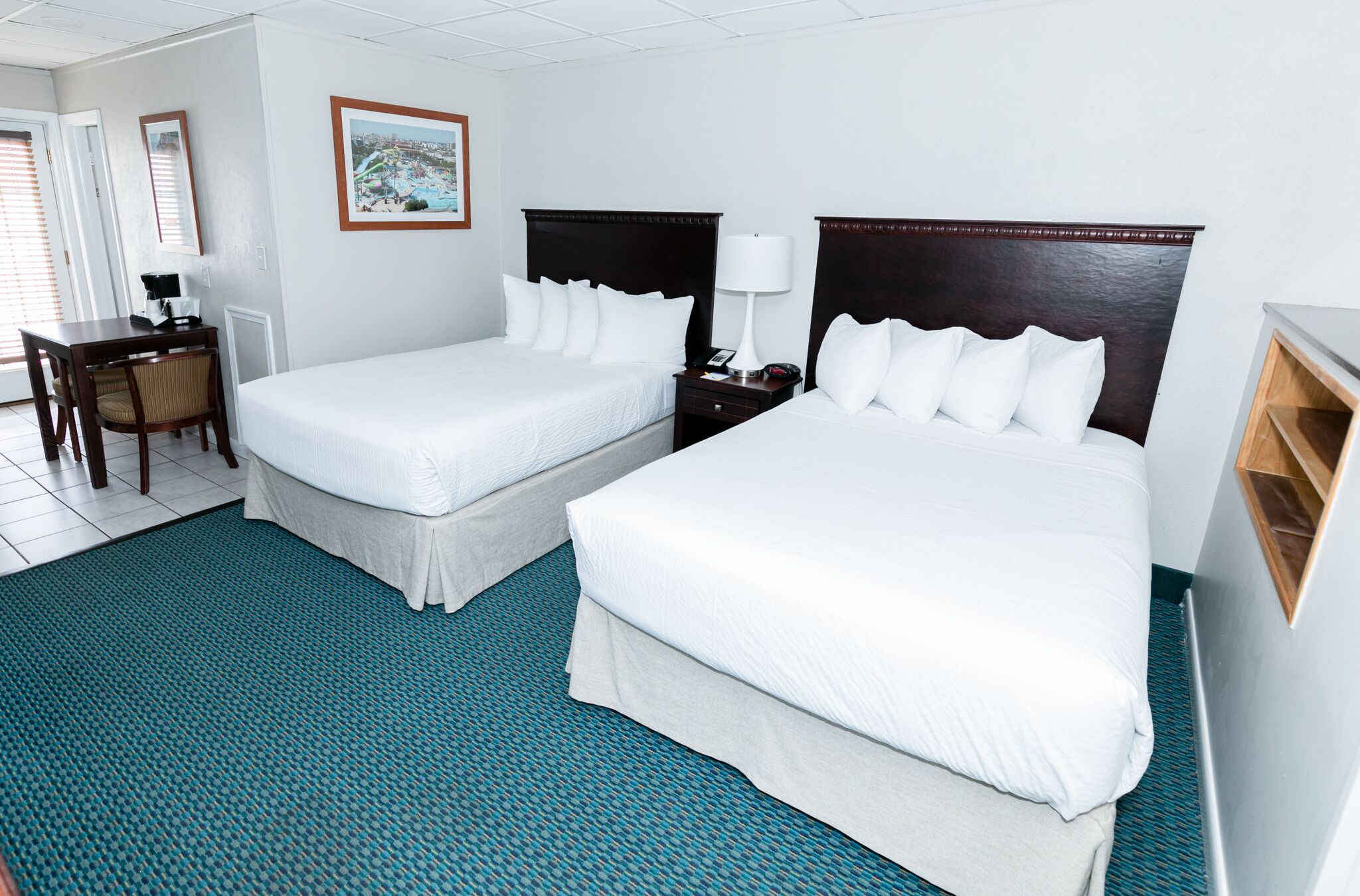 Ein Hotelzimmer mit zwei Betten, einem Schreibtisch und einem Stuhl.