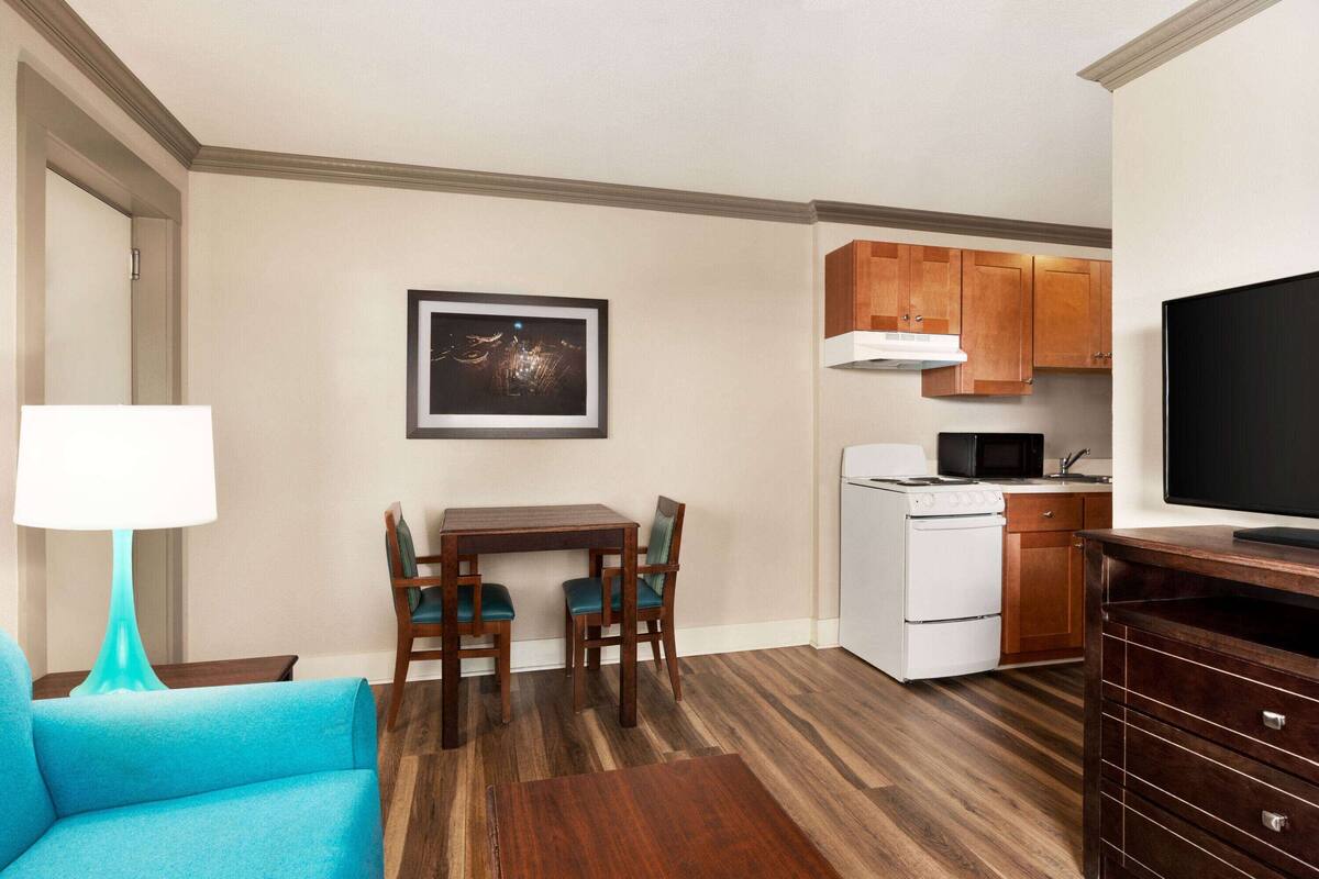A compact living space with a dining area, kitchenette, and a television.