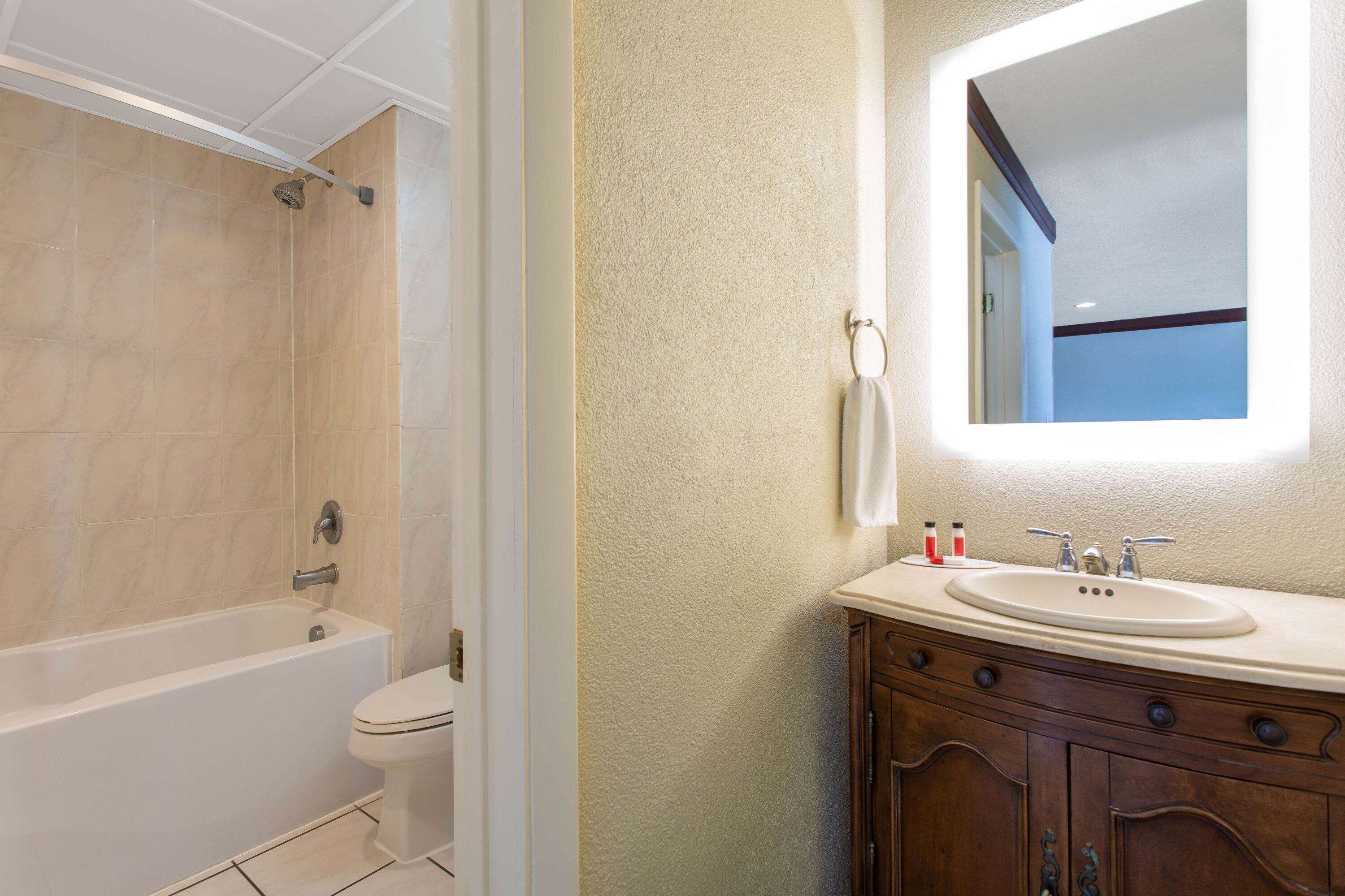 A bathroom with a bathtub, toilet, sink, and vanity.