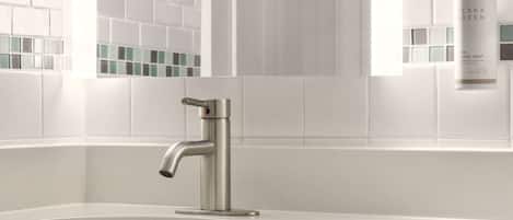 A modern bathroom with a sleek, metallic faucet, a white sink, and a window with a view of the city.