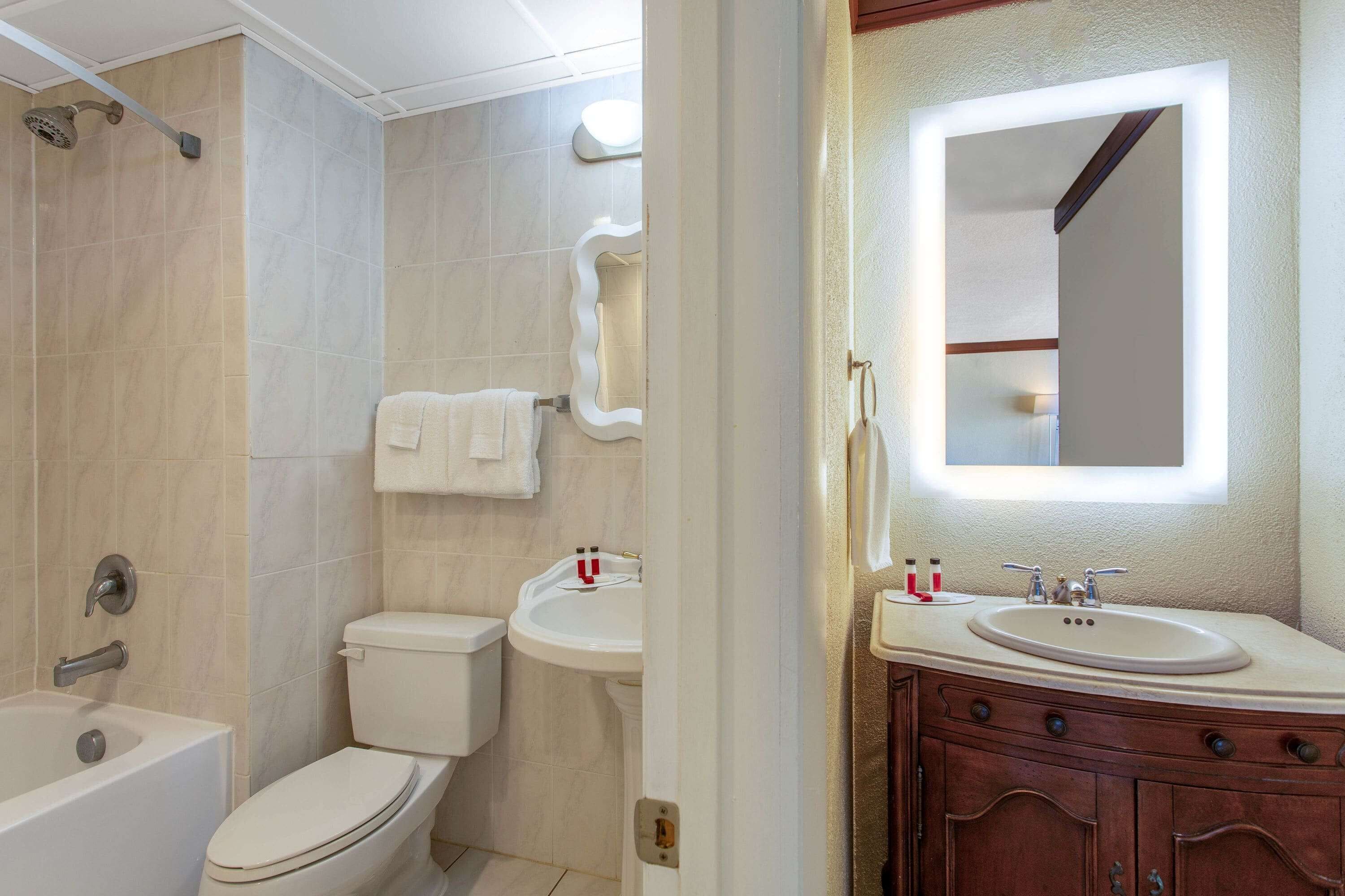 Un bagno con vasca, water, lavandino e mobile contenitore con specchio.