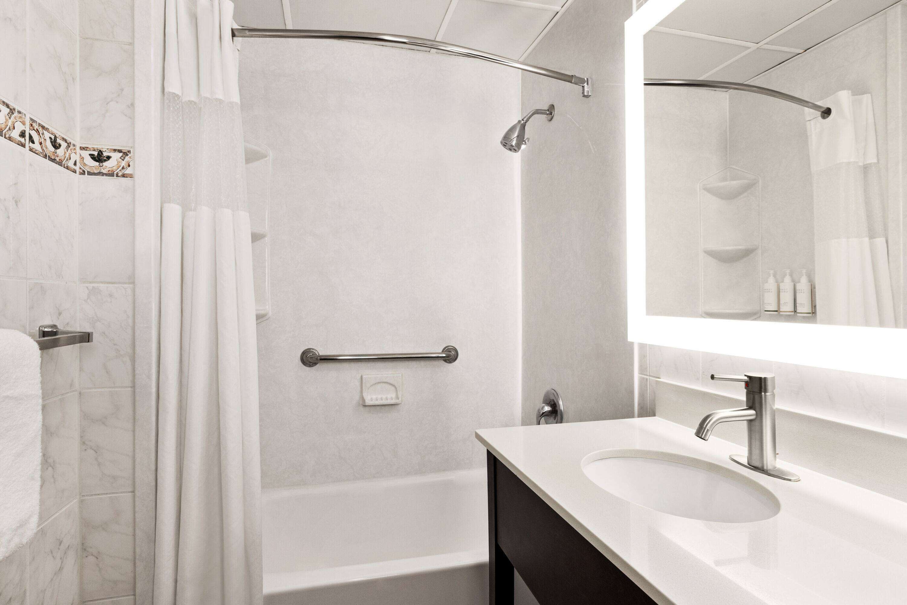 A modern bathroom with a bathtub, shower, and a vanity with a sink.
