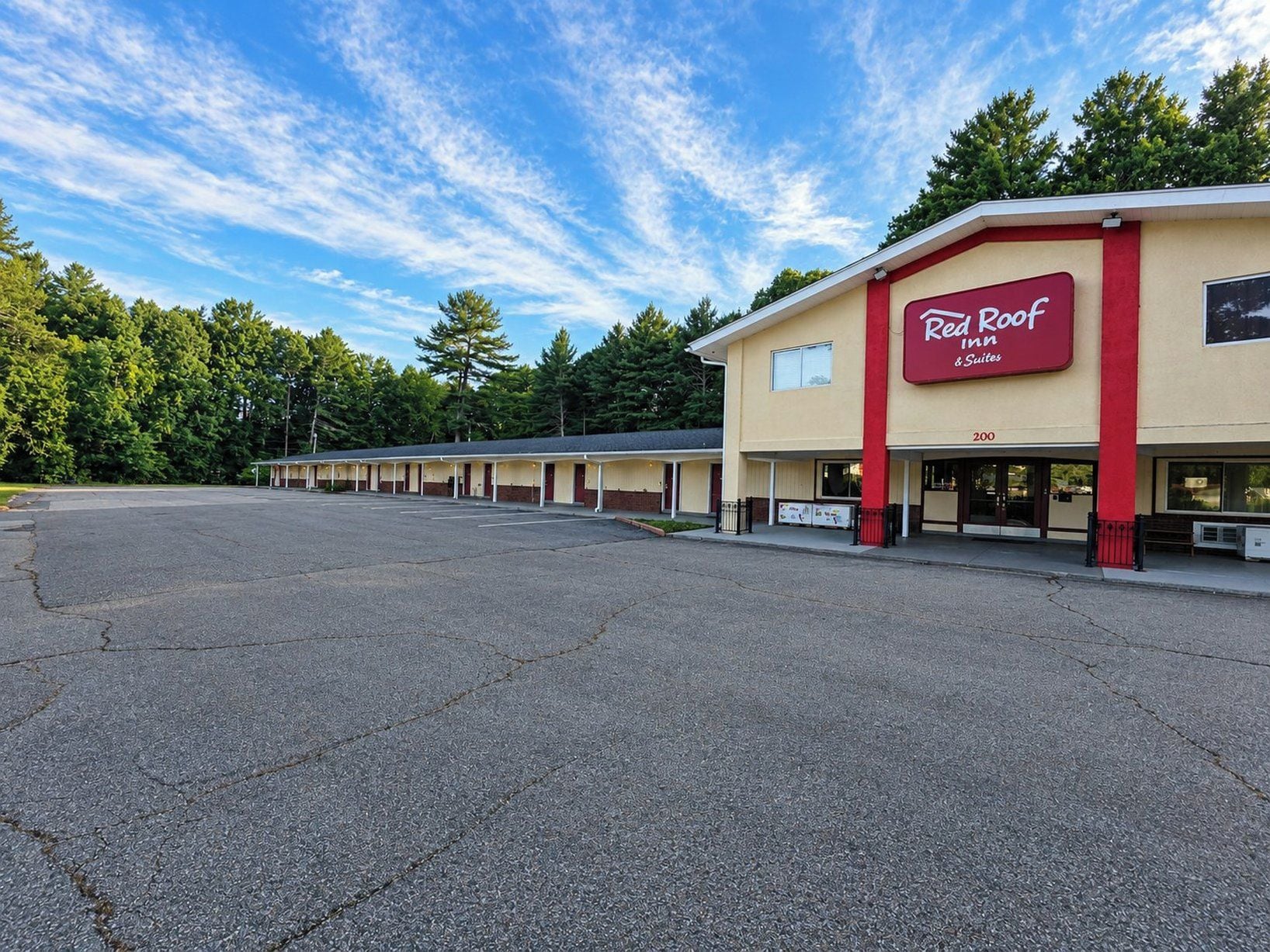 A Red Roof Inn & Suites with a large parking lot and a row of single-story motel rooms.