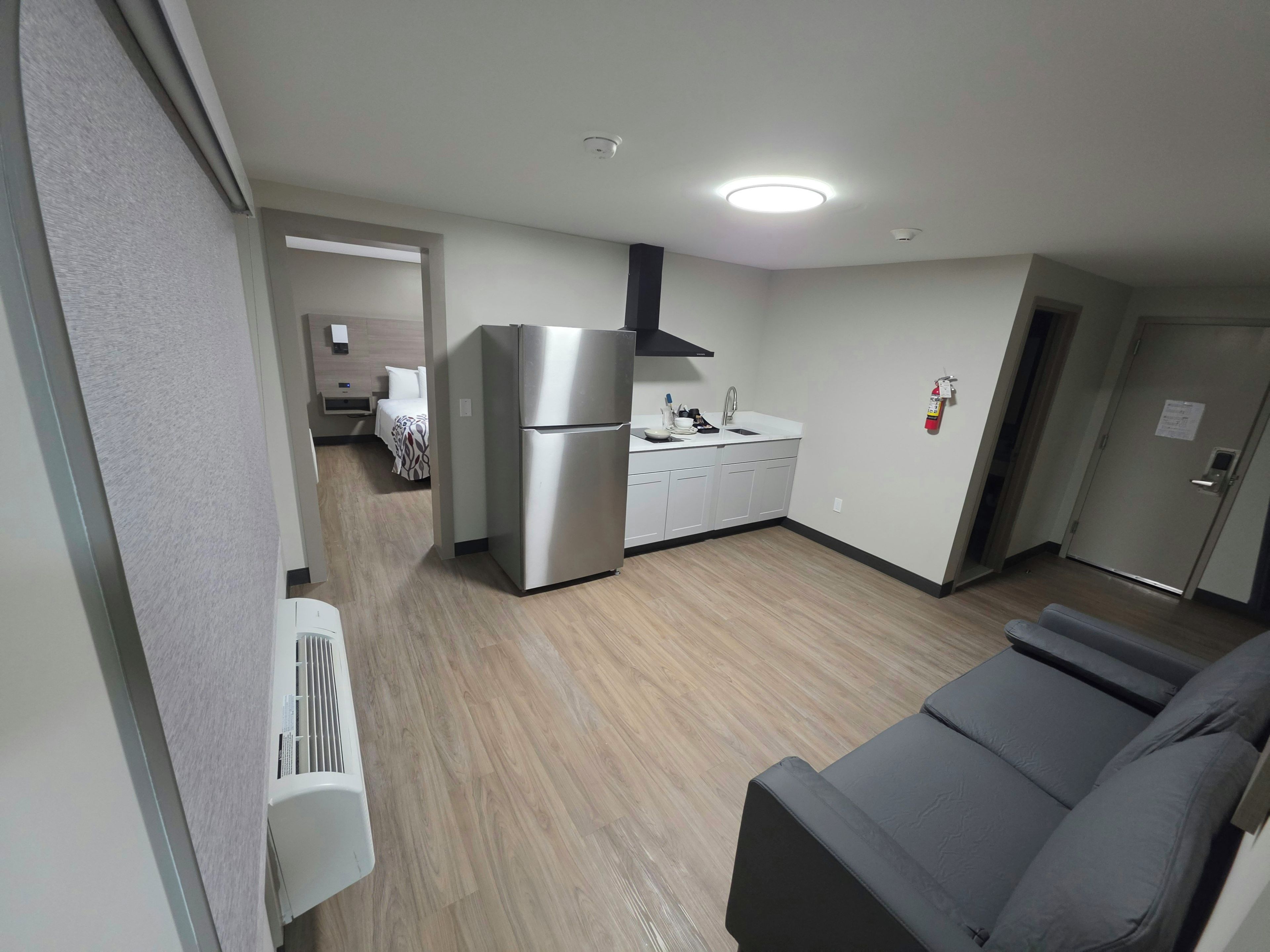 Un espacio habitable compacto con kitchenette, sofá y cama.
