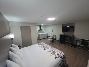 A hotel room with a bed, a desk, a chair, a television, and a kitchenette. - Red Roof Inn Sutton (Sutton)