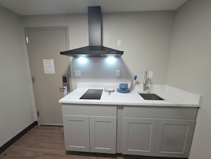 A kitchen with a double sink, a black range hood, and a white countertop.