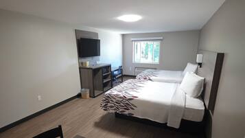 A compact hotel room with a bed, a desk, a chair, a television, and a window.