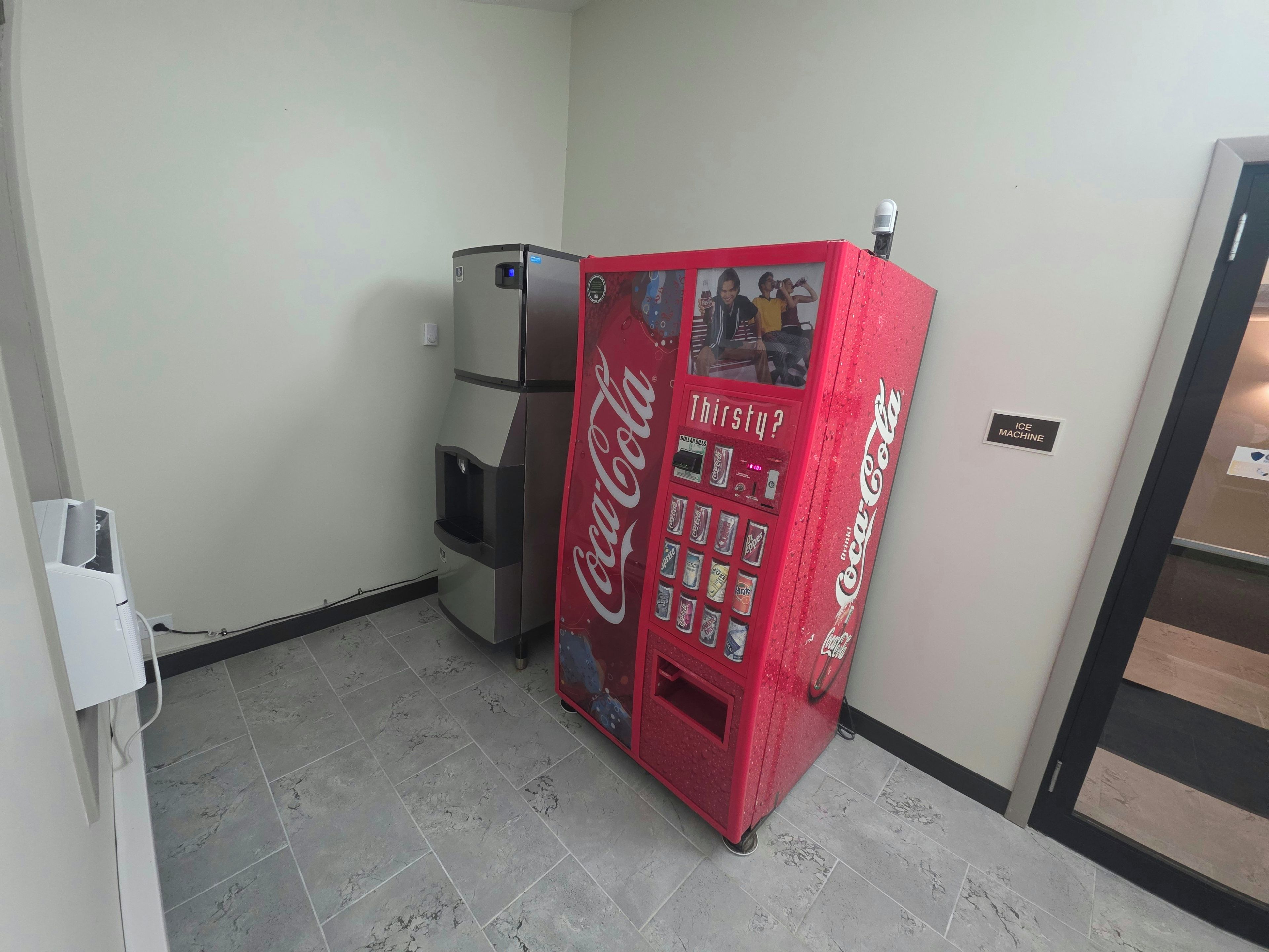 A vending machine with a Coca-Cola logo, a digital display, and a sign indicating it dispenses ice.
