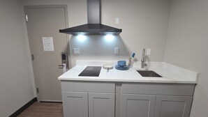 Una cocina con un lavamanos doble, una estufa, armarios y una campana extractora de acero inoxidable.