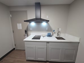 Una cocina con un lavamanos doble, una estufa, armarios y una campana extractora de acero inoxidable.