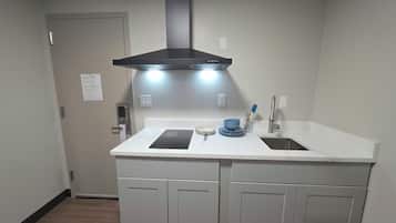 A kitchen with a double sink, a black range hood, and a white countertop.