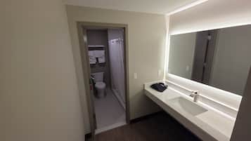 A hotel bathroom with a toilet, a sink, a mirror, and a shower curtain.