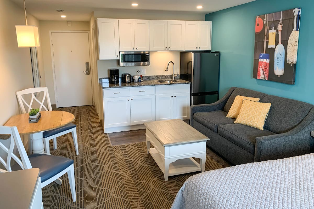 Un espacio habitable compacto con kitchenette, comedor y zona de estar.
