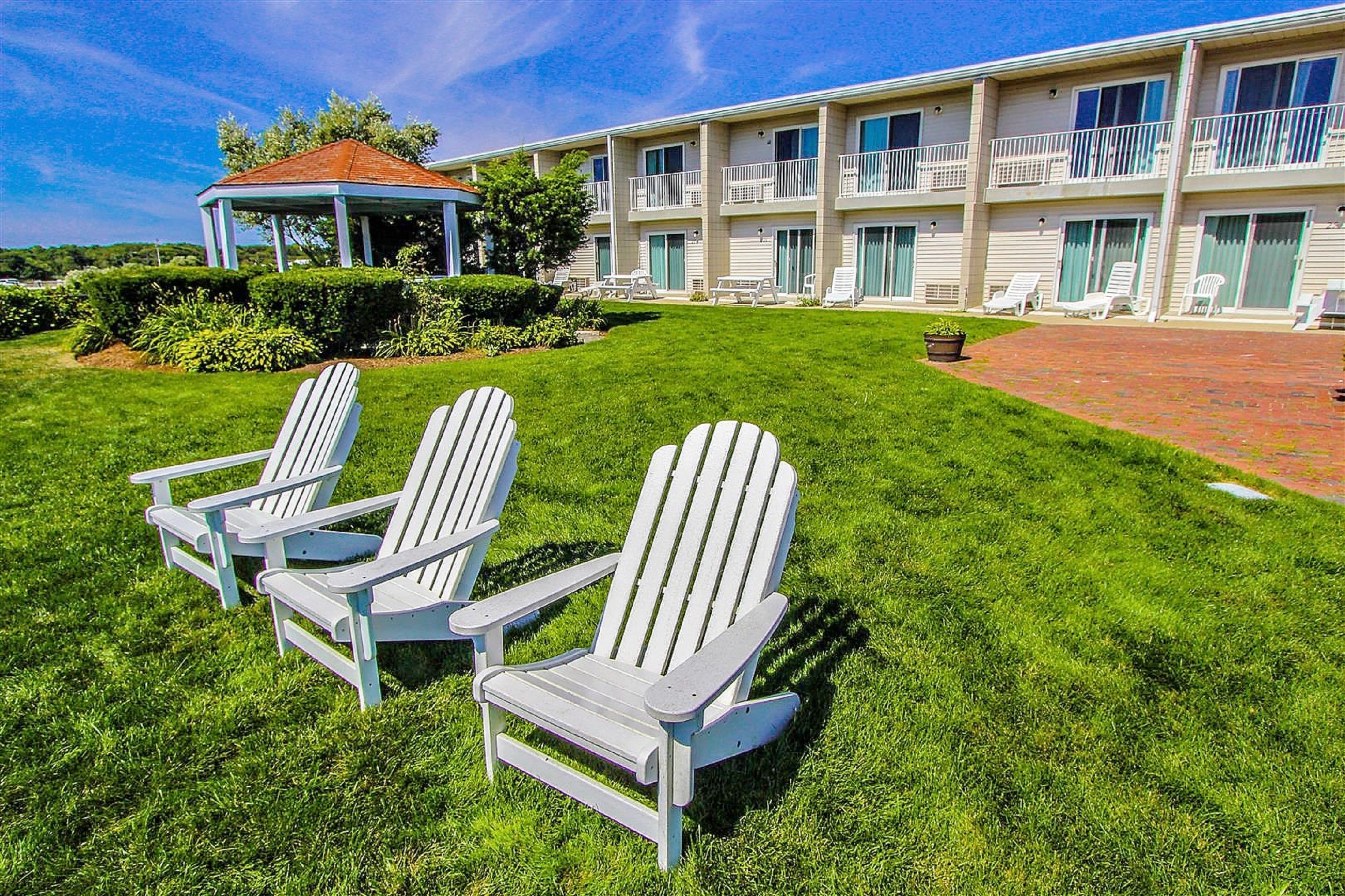 A hotel with a covered patio, outdoor seating, and a well-maintained lawn.