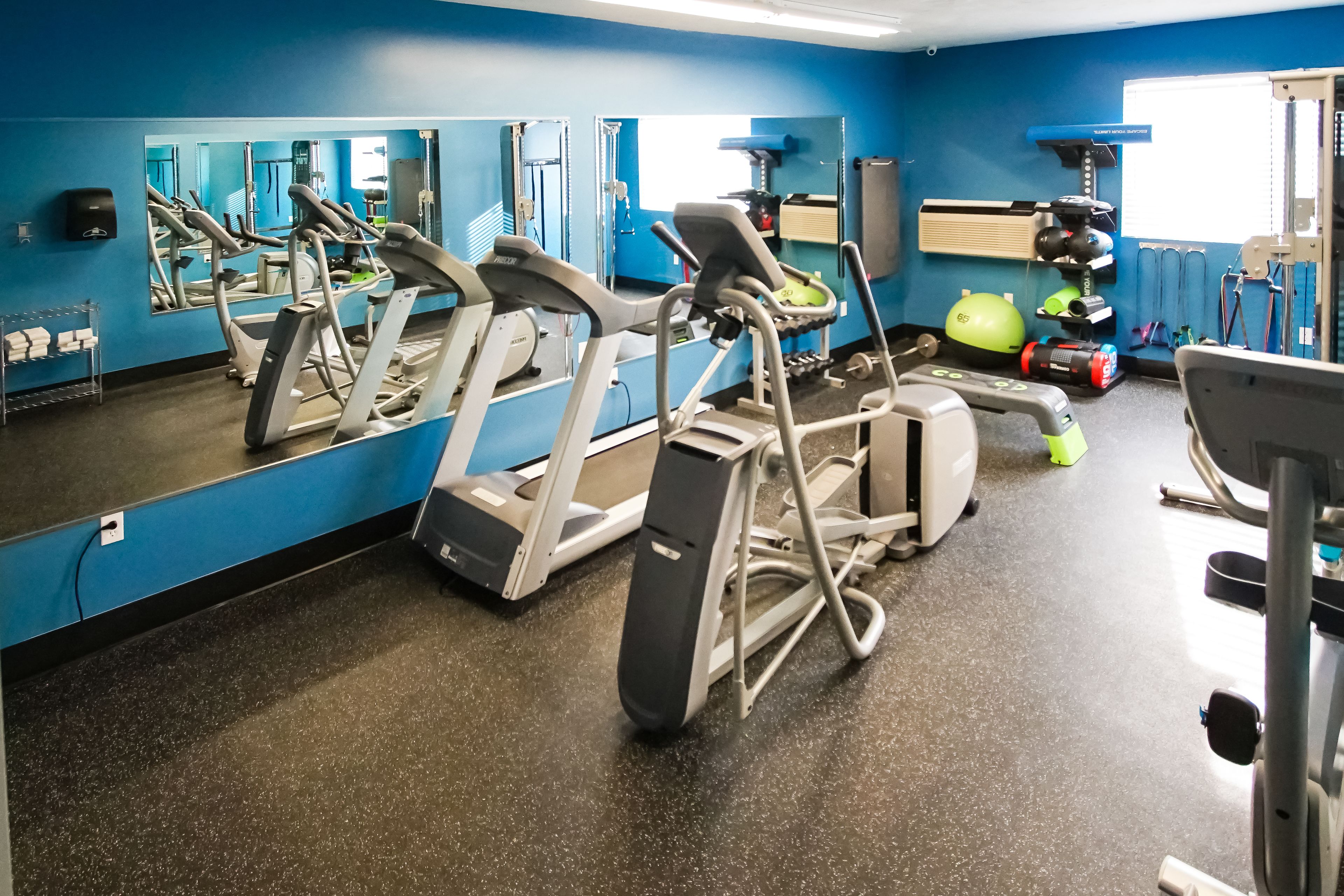 A gym with treadmills, exercise bikes, and a mirrored wall.
