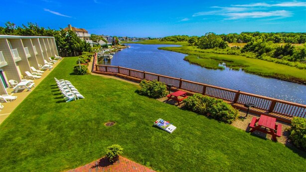 A hotel with a grassy lawn, a river view, and a pool area with lounge chairs.