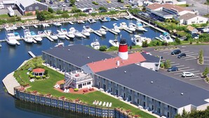 A marina with docked boats, a lighthouse, and a building with outdoor seating.