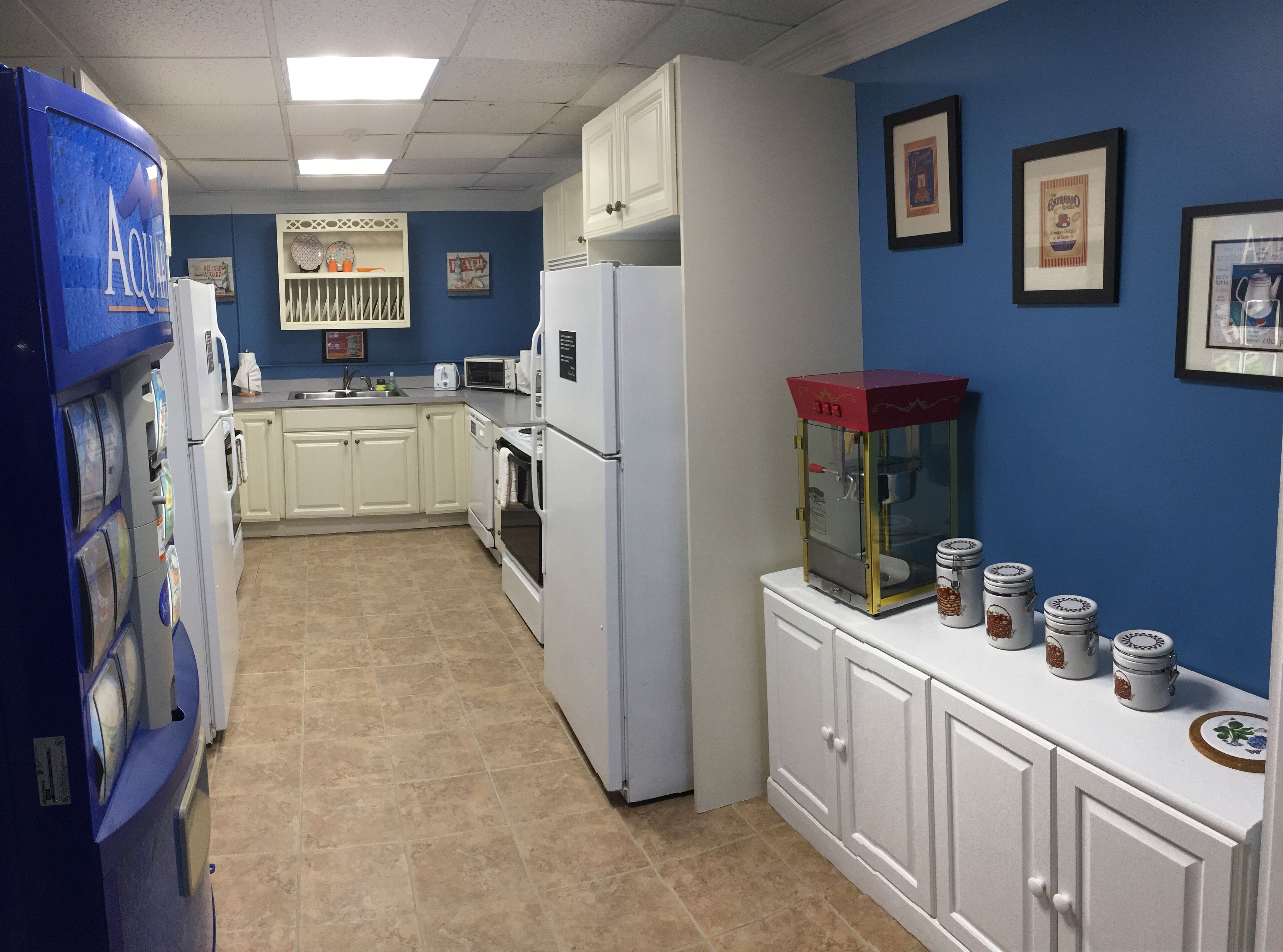A kitchen with white cabinets, a microwave, a refrigerator, and a water dispenser.