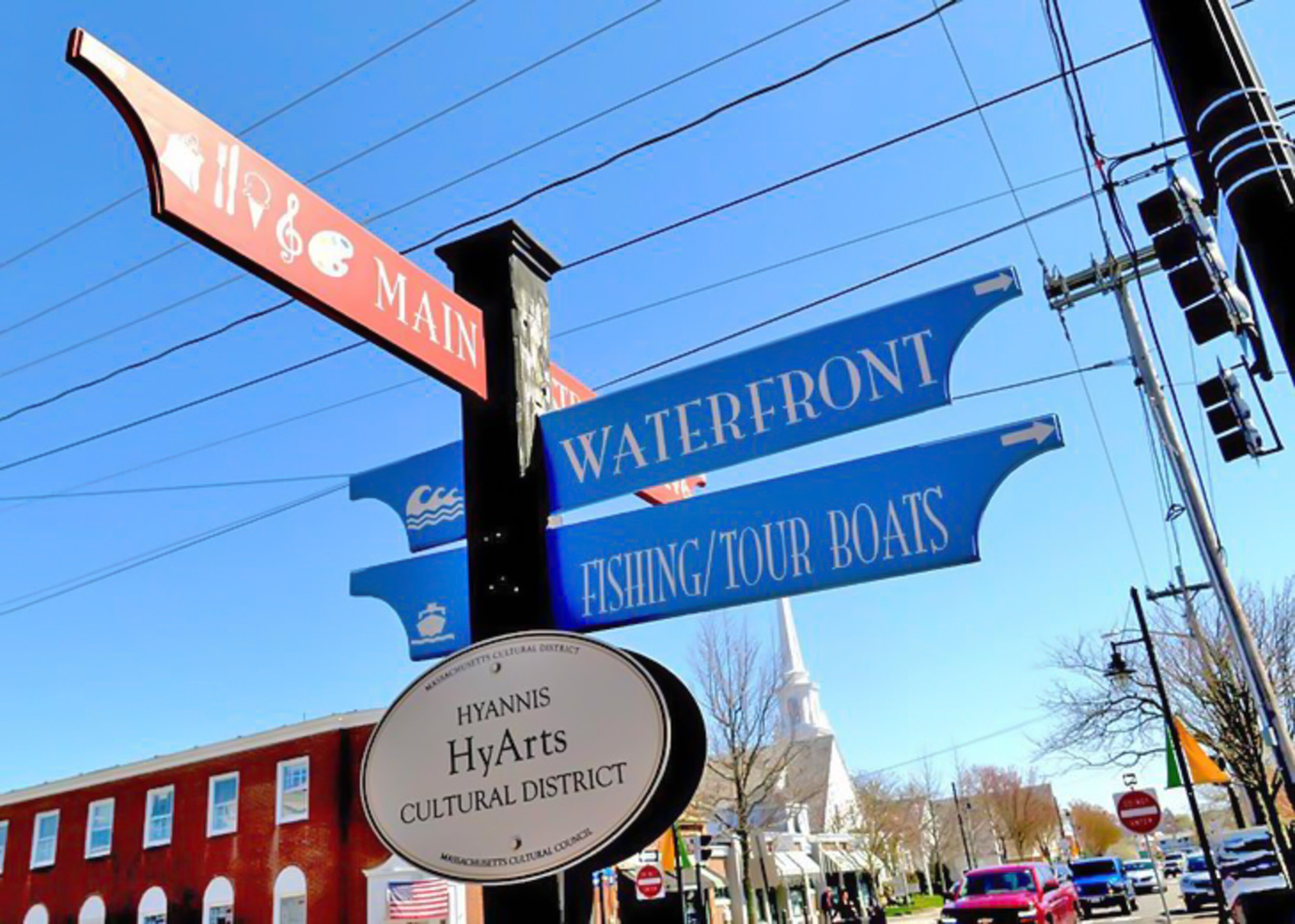 Un panneau de signalisation indiquant la direction du front de mer, des quais de pêche et des bateaux de tourisme, ainsi que du quartier culturel Hyannis HyArts.
