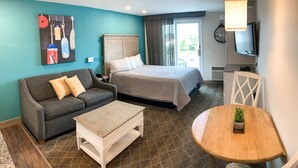 A hotel room with a bed, a sofa, a coffee table, a TV, and a small table with a plant.