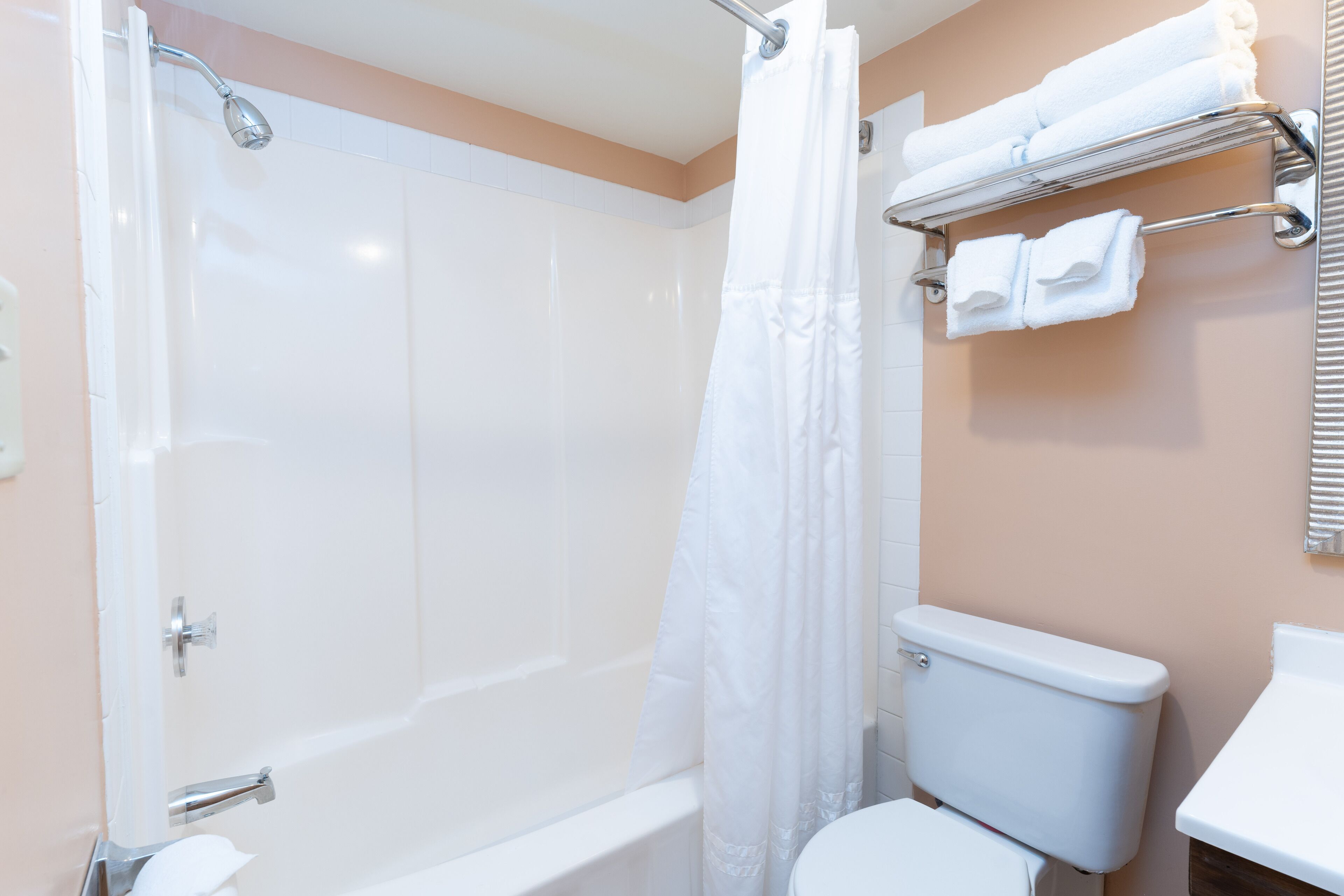 A bathroom with a bathtub, toilet, and a towel rack with towels.