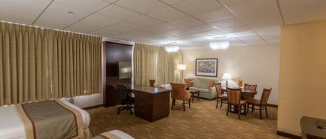 A hotel room with two beds, a desk, a chair, a sofa, and a dining table.