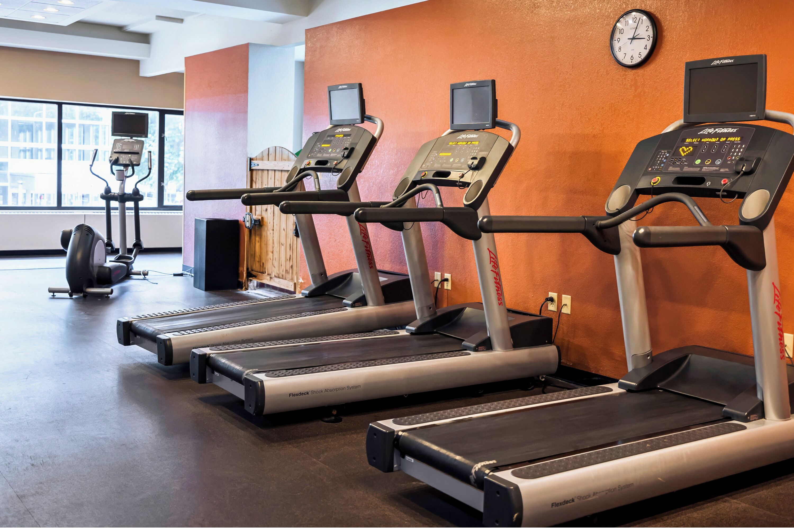 Un gimnasio con cintas de correr, una bicicleta estática y una máquina de remo.