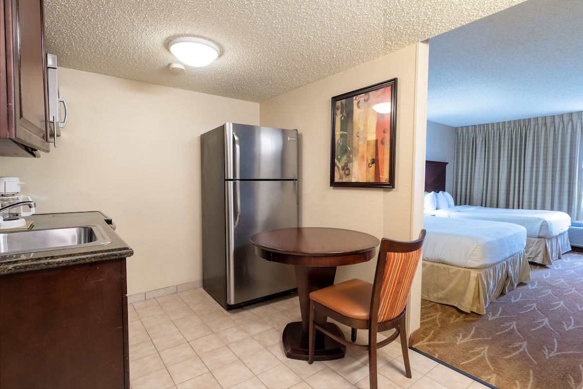 A hotel room with a kitchenette, a bed, a dining table, and a chair.