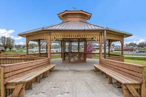 Situated on a paved area, this gazebo offers a serene view of the surrounding landscape and features a central open area with benches.