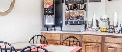 A café with a counter, espresso machines, a water dispenser, and framed pictures on the wall.