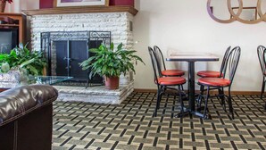 Un hall con chimenea, una mesa con cuatro sillas y una alfombra estampada.