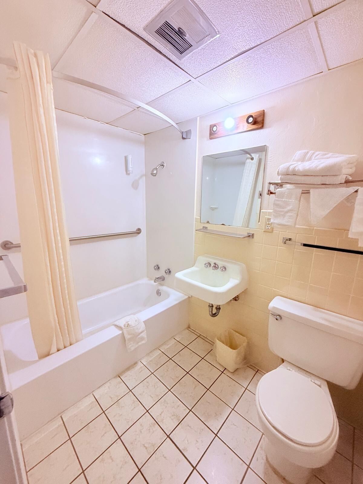 Een badkamer met een bad, een wastafel, een toilet en een spiegel.
